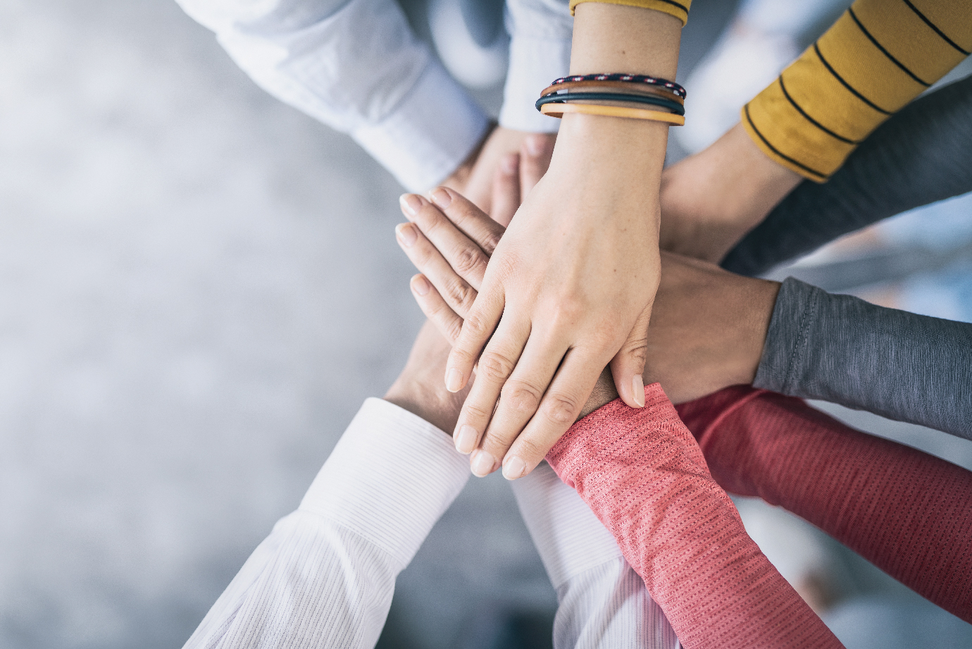 A group of people laying their hands on top of each other