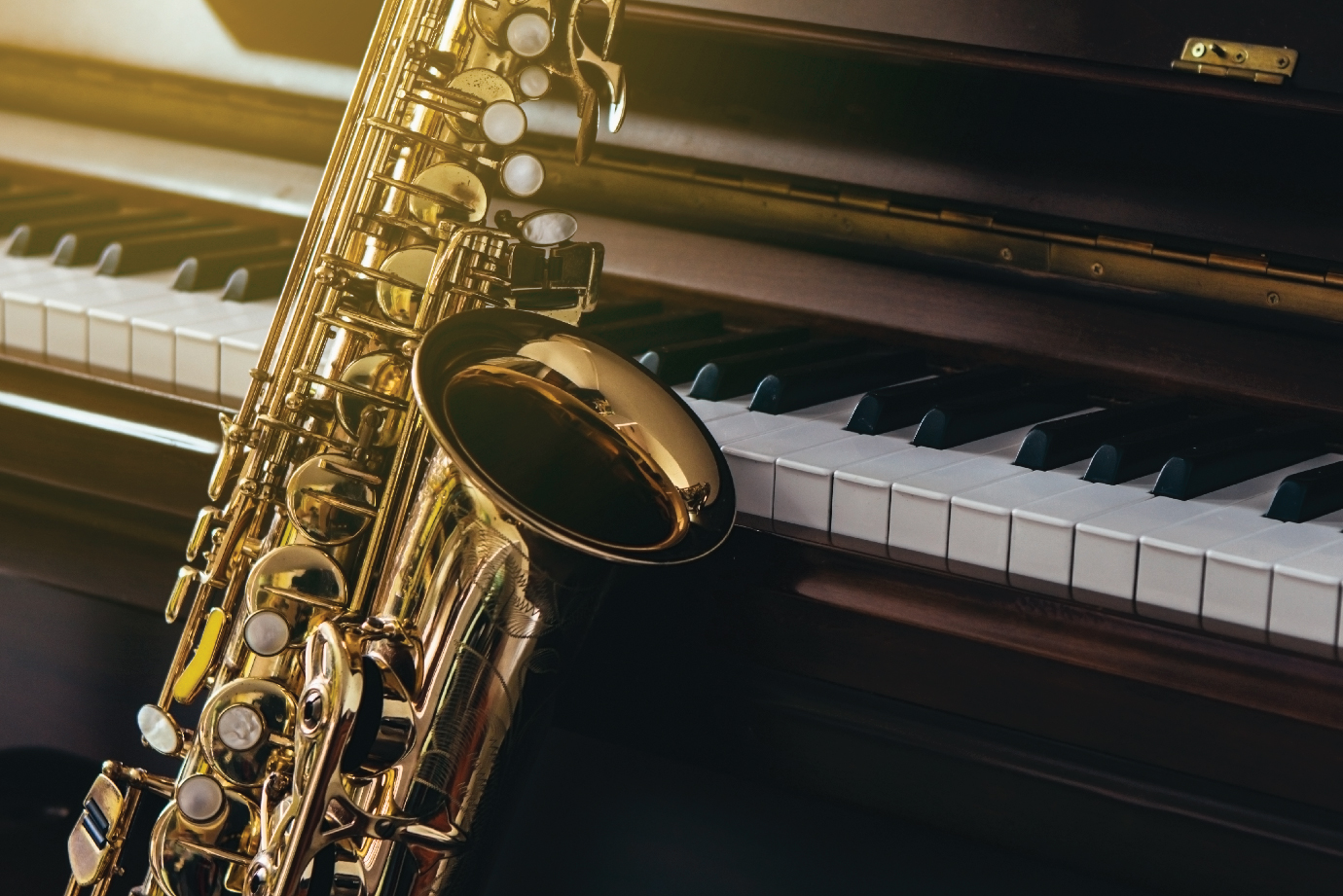 A saxophone resting against a piano