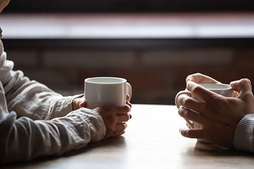 Two people sitting across each other having coffee