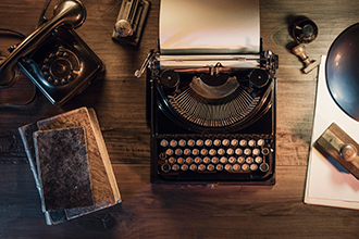 Desk with a typewriter, book, phone and lamp