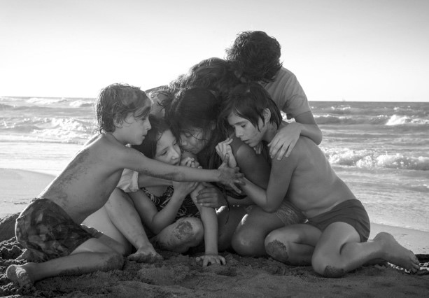 Several kids on a beach hugging another kid - a scene from the movie Unorthodox