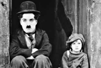 A still from a Charlie Chaplin movie featuring the star sitting next to a little boy