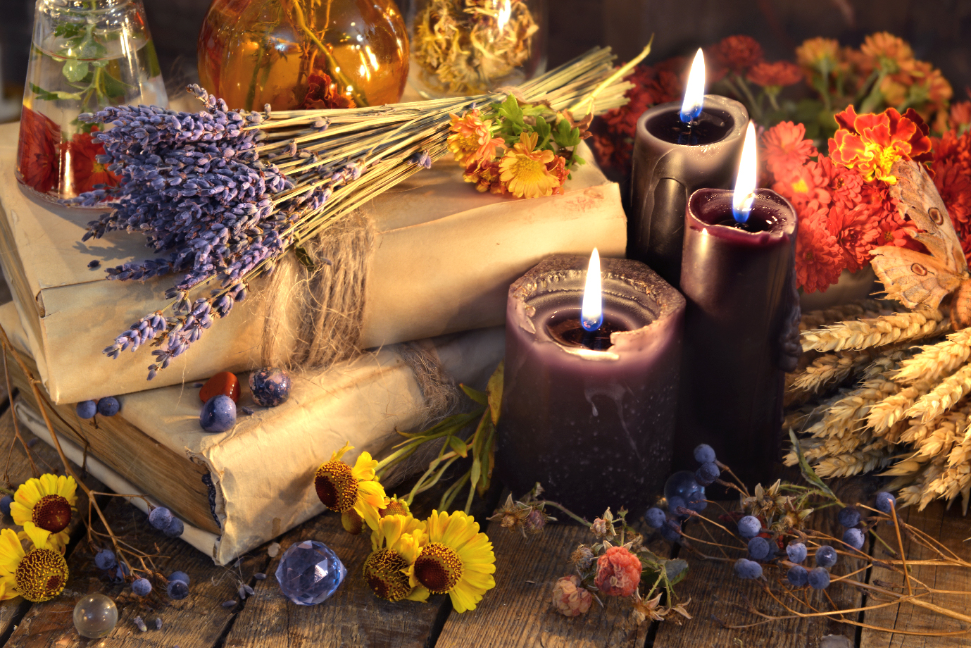 A scene depicting lit scented candles, dried flowers and essential oils