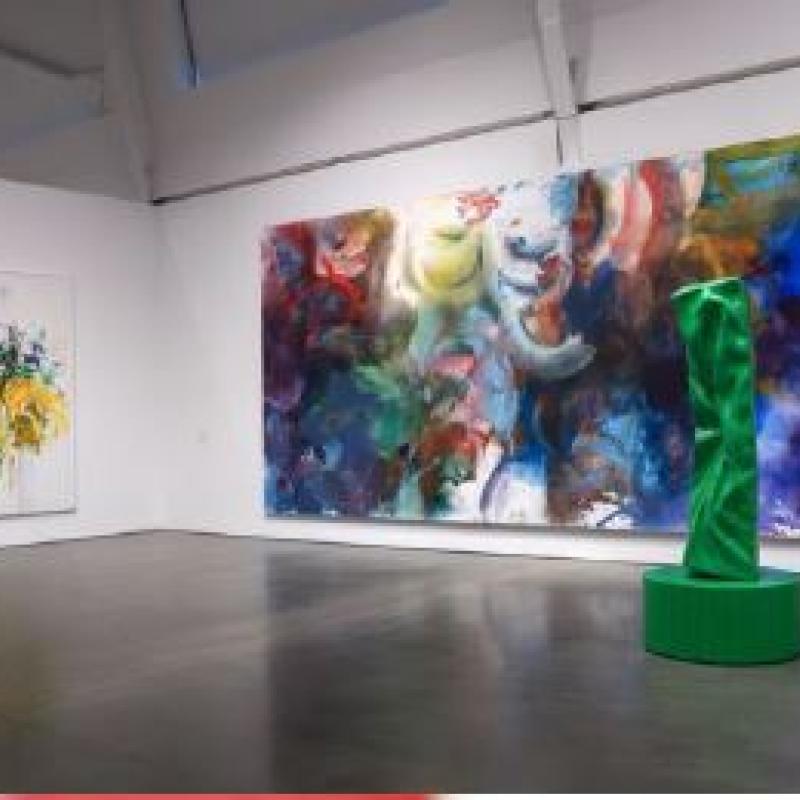 Two large colorful art exhibits and a green sculpture in the middle of the room in an art museum