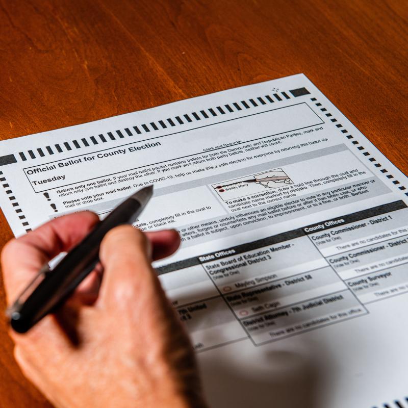 hand holding pen filling out a ballot