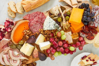 A smorgasboard of fruit, bread, meat and cheese on a table